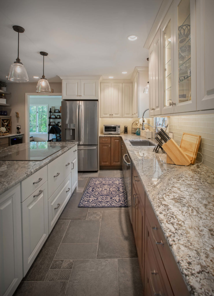 Burlington kitchen remodel showing island with flush stove top and base cabinets, perimeter cabinets with glass doors, and granite counters,.