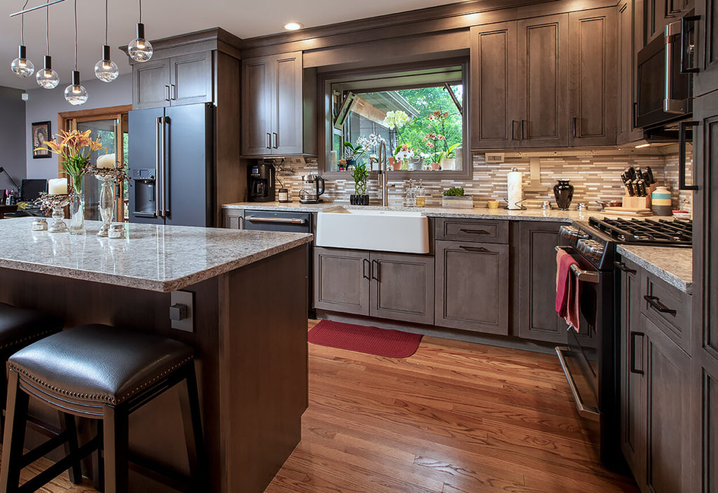 View to the in this Wallingford, CT kitchen remodel, showing Ultracraft Cherry Wood cabinets with Wicker Park door style in Coastal Grey stain finish and Cambria New Quay quartz counters.